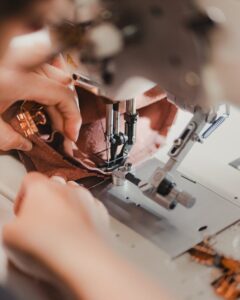 Hands skillfully sewing a piece of fabric using a sewing machine.